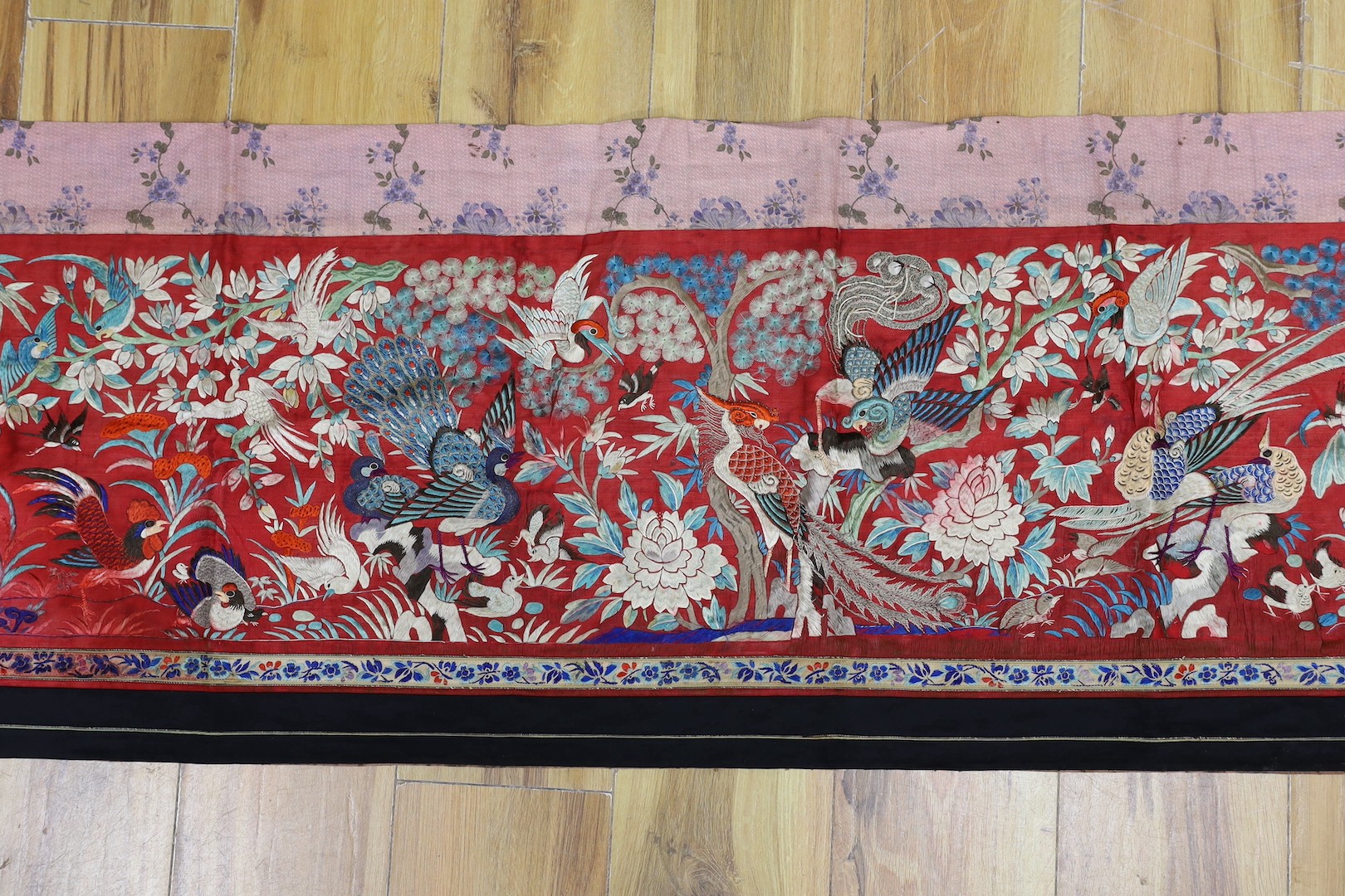 An early 20th century Chinese embroidered silk helmet multi coloured embroidery on a red background depicting oriental birds. 183cm x 47.5cm. 183cm x 47.5cm